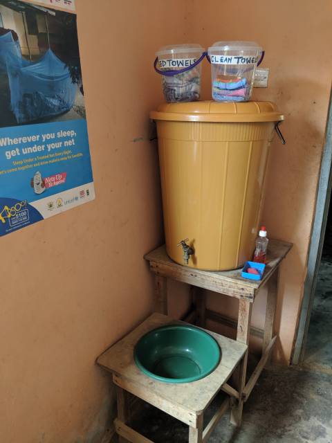 a handwashing station with a yellow barrell dripping into a green basin.