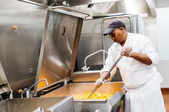 A cook prepares food in a large industrial kitchen