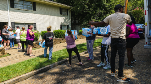 A line of people pass along crates of water